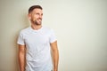 Young handsome man wearing casual white t-shirt over isolated background looking away to side with smile on face, natural Royalty Free Stock Photo