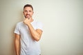 Young handsome man wearing casual white t-shirt over isolated background looking confident at the camera smiling with crossed arms Royalty Free Stock Photo