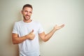 Young handsome man wearing casual white t-shirt over isolated background Showing palm hand and doing ok gesture with thumbs up, Royalty Free Stock Photo