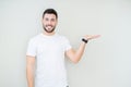 Young handsome man wearing casual white t-shirt over isolated background smiling cheerful presenting and pointing with palm of Royalty Free Stock Photo