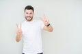 Young handsome man wearing casual white t-shirt over isolated background smiling looking to the camera showing fingers doing Royalty Free Stock Photo