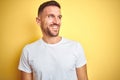 Young handsome man wearing casual white t-shirt over yellow isolated background looking away to side with smile on face, natural Royalty Free Stock Photo