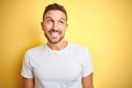 Young handsome man wearing casual white t-shirt over yellow isolated background smiling looking side and staring away thinking Royalty Free Stock Photo