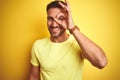 Young handsome man wearing casual yellow t-shirt over yellow isolated background doing ok gesture with hand smiling, eye looking Royalty Free Stock Photo