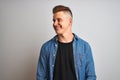 Young handsome man wearing denim shirt standing over isolated white background looking away to side with smile on face, natural Royalty Free Stock Photo