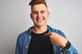 Young handsome man wearing denim shirt standing over isolated white background with surprise face pointing finger to himself Royalty Free Stock Photo