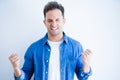 Young handsome man wearing denim shirt standing over isolated white background very happy and excited doing winner gesture with Royalty Free Stock Photo