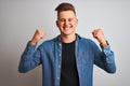 Young handsome man wearing denim shirt standing over isolated white background very happy and excited doing winner gesture with Royalty Free Stock Photo