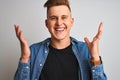 Young handsome man wearing denim shirt standing over isolated white background very happy and excited, winner expression Royalty Free Stock Photo