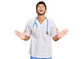 Young handsome man wearing doctor uniform and stethoscope celebrating mad and crazy for success with arms raised and closed eyes Royalty Free Stock Photo