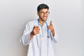 Young handsome man wearing doctor uniform and stethoscope pointing fingers to camera with happy and funny face Royalty Free Stock Photo