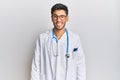 Young handsome man wearing doctor uniform and stethoscope winking looking at the camera with sexy expression, cheerful and happy Royalty Free Stock Photo