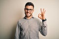 Young handsome man wearing elegant shirt and glasses over isolated white background smiling positive doing ok sign with hand and Royalty Free Stock Photo