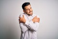 Young handsome man wearing elegant shirt standing over isolated white background Hugging oneself happy and positive, smiling Royalty Free Stock Photo