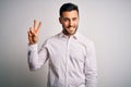 Young handsome man wearing elegant shirt standing over isolated white background smiling looking to the camera showing fingers Royalty Free Stock Photo