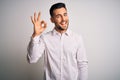 Young handsome man wearing elegant shirt standing over isolated white background smiling positive doing ok sign with hand and Royalty Free Stock Photo