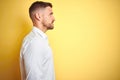 Young handsome man wearing elegant white shirt over yellow isolated background looking to side, relax profile pose with natural Royalty Free Stock Photo