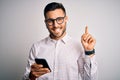 Young handsome man wearing glasses having conversation using smartphone and earphones surprised with an idea or question pointing Royalty Free Stock Photo