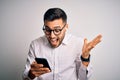 Young handsome man wearing glasses having conversation using smartphone and earphones very happy and excited, winner expression Royalty Free Stock Photo