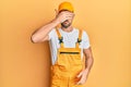 Young handsome man wearing handyman uniform over yellow background covering eyes with hand, looking serious and sad