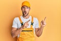Young handsome man wearing handyman uniform pointing to the side in shock face, looking skeptical and sarcastic, surprised with Royalty Free Stock Photo