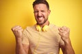 Young handsome man wearing headphones listening to music over yellow isolated background very happy and excited doing winner Royalty Free Stock Photo