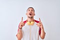 Young handsome man wearing headphones over isolated background amazed and surprised looking up and pointing with fingers and Royalty Free Stock Photo