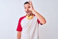 Young handsome man wearing headphones over isolated background doing ok gesture with hand smiling, eye looking through fingers Royalty Free Stock Photo