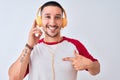 Young handsome man wearing headphones over isolated background with surprise face pointing finger to himself Royalty Free Stock Photo