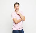 Young handsome man, wearing pink shirt looking at camera thoughtful holding hand on chin as thinkings Royalty Free Stock Photo