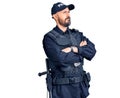 Young handsome man wearing police uniform looking to the side with arms crossed convinced and confident Royalty Free Stock Photo