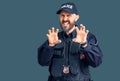 Young handsome man wearing police uniform smiling funny doing claw gesture as cat, aggressive and sexy expression Royalty Free Stock Photo