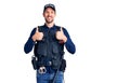 Young handsome man wearing police uniform success sign doing positive gesture with hand, thumbs up smiling and happy