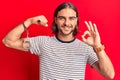 Young handsome man wearing prisoner handcuffs doing ok sign with fingers, smiling friendly gesturing excellent symbol