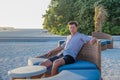 Young  handsome man wearing shirt resting on the couch under roof near beach at the tropical island luxury resort Royalty Free Stock Photo