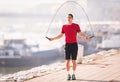 Young man wearing sportswear skipping rope at quay during autumn Royalty Free Stock Photo