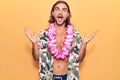 Young handsome man wearing swimwear and hawaiian lei celebrating victory with happy smile and winner expression with raised hands Royalty Free Stock Photo