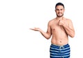 Young handsome man wearing swimwear showing palm hand and doing ok gesture with thumbs up, smiling happy and cheerful Royalty Free Stock Photo