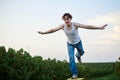 Young handsome man, wearing torn jeans and white t-shirt, sitting on yellow stool on green field, thinking. Artistic education Royalty Free Stock Photo