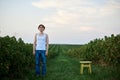 Young handsome man, wearing torn jeans and white t-shirt, standing by yellow stool on green field, having fun. Artistic education Royalty Free Stock Photo