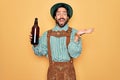 Young handsome man wearing tratidional german octoberfest custome and drinking beer from bottle very happy and excited, winner