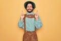 Young handsome man wearing tratidional german octoberfest custome for Germany festival gesturing finger crossed smiling with hope Royalty Free Stock Photo