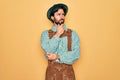 Young handsome man wearing tratidional german octoberfest custome for Germany festival with hand on chin thinking about question,