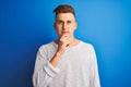 Young handsome man wearing white casual t-shirt standing over isolated blue background serious face thinking about question, very Royalty Free Stock Photo