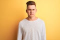 Young handsome man wearing white casual t-shirt standing over isolated yellow background depressed and worry for distress, crying Royalty Free Stock Photo