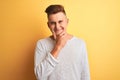 Young handsome man wearing white casual t-shirt standing over isolated yellow background looking confident at the camera smiling Royalty Free Stock Photo