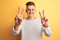 Young handsome man wearing white casual t-shirt standing over isolated yellow background smiling looking to the camera showing Royalty Free Stock Photo