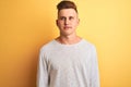 Young handsome man wearing white casual t-shirt standing over isolated yellow background smiling looking to the side and staring Royalty Free Stock Photo
