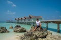 Young handsome man wearing white t-shirt and black shorts sitting on rocks at tropical beach at the island luxury resort Royalty Free Stock Photo