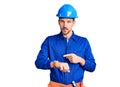 Young handsome man wearing worker uniform and hardhat looking at the watch time worried, afraid of getting late Royalty Free Stock Photo